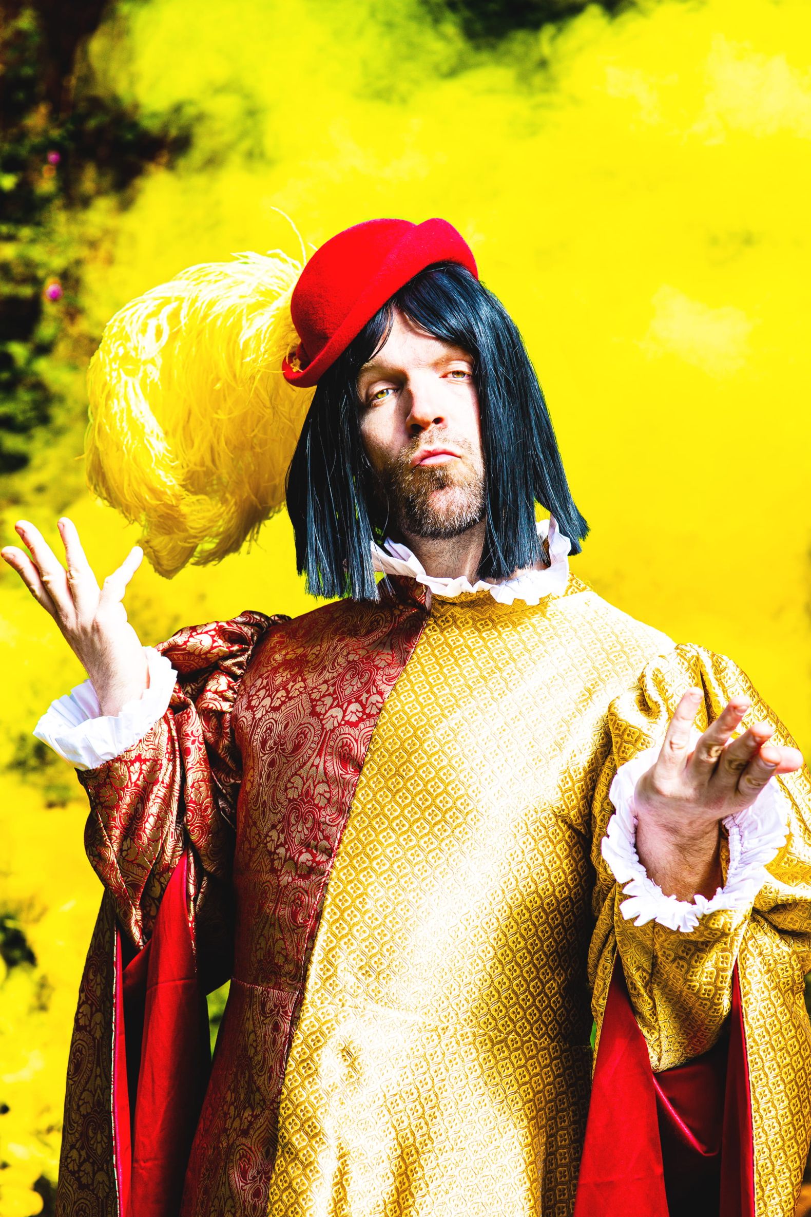 Robin Hood - the Dukes Park Show in Williamson Park: Lord Foppingham gestures to the viewer in a red and gold outift with clouds of golden smoke behind him.