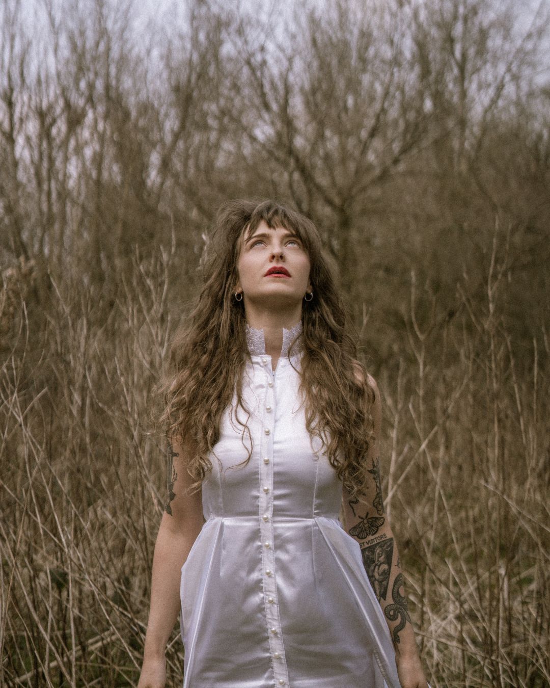 performer in a silk dress stood in field looking up to the sky -Macbeth by HER Productions at The Dukes, Lancaster