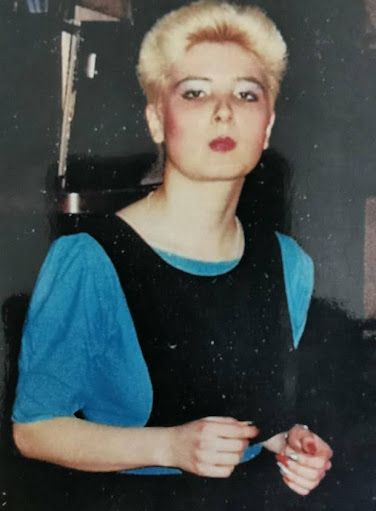 film photo of woman in blue top and black pinafore dress