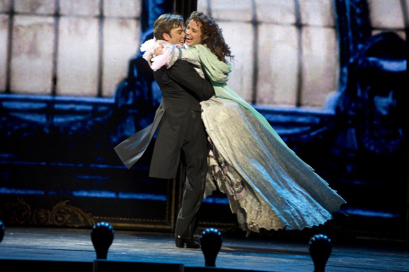 a happy couple in period costume...the girl being swung around, her feet off the floor