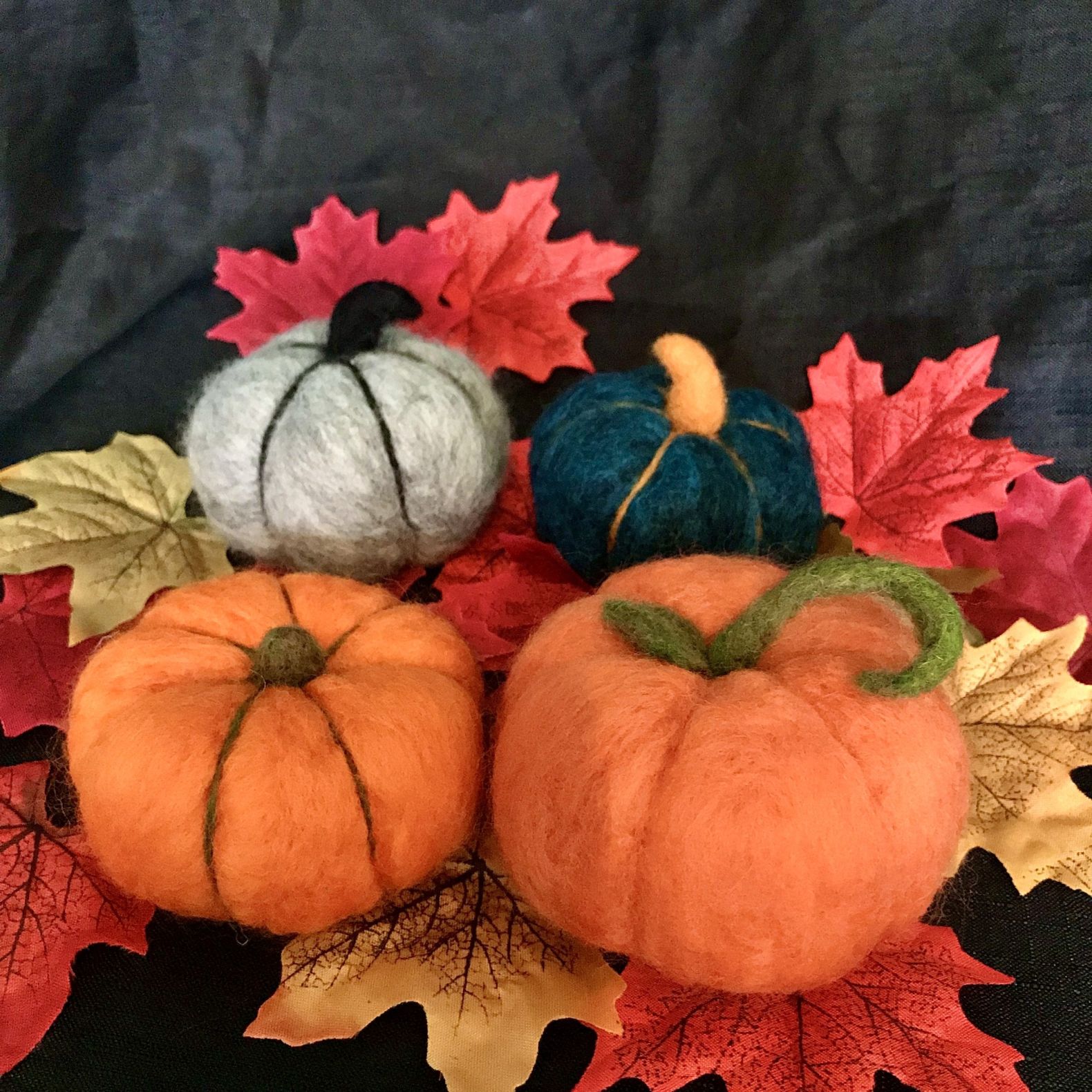 a photograph of felt pumpkins on Autumnal leaves