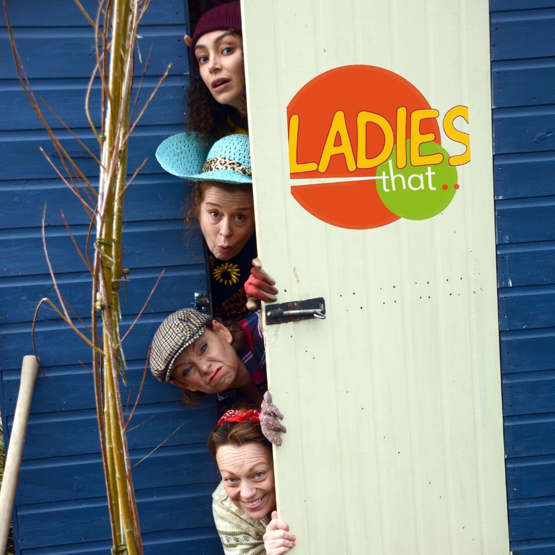 4 ladies in gardening gear peering around a shed door