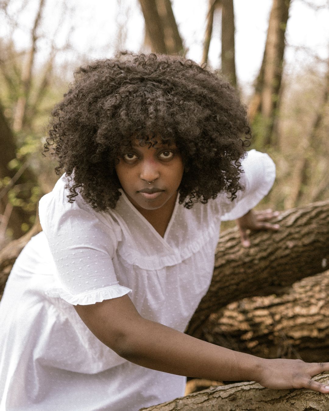 performer climbing over logs in a white outfit - Macbeth by HER Productions at The Dukes, Lancaster