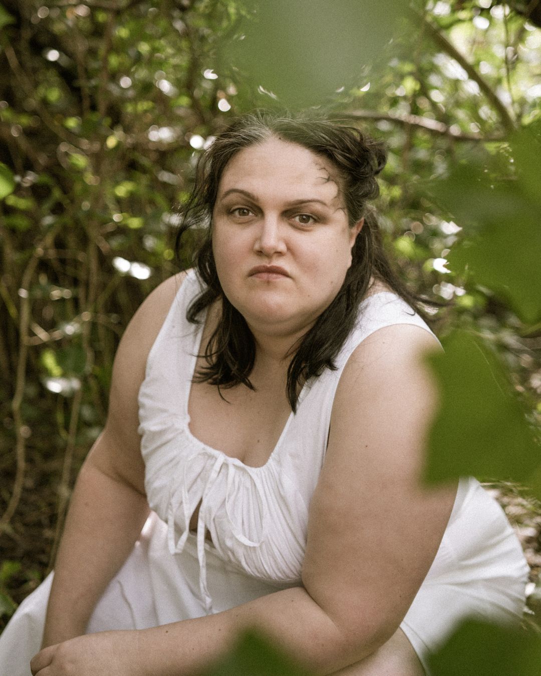 performer kneeling between leafs wearing a white outfit - Macbeth by HER Productions at The Dukes, Lancaster
