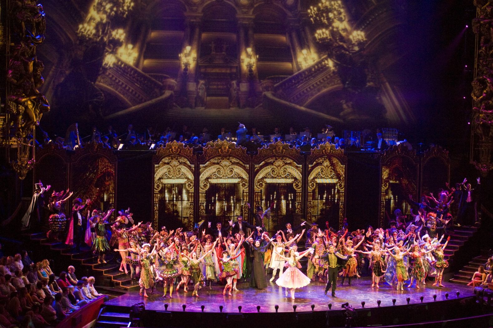 the full cast of Phantom of the Opera on stage with their arms raised as though in response to appause