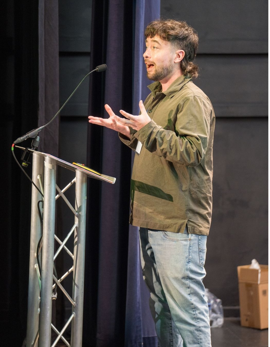 Kieran stood on stage talking into a microphone