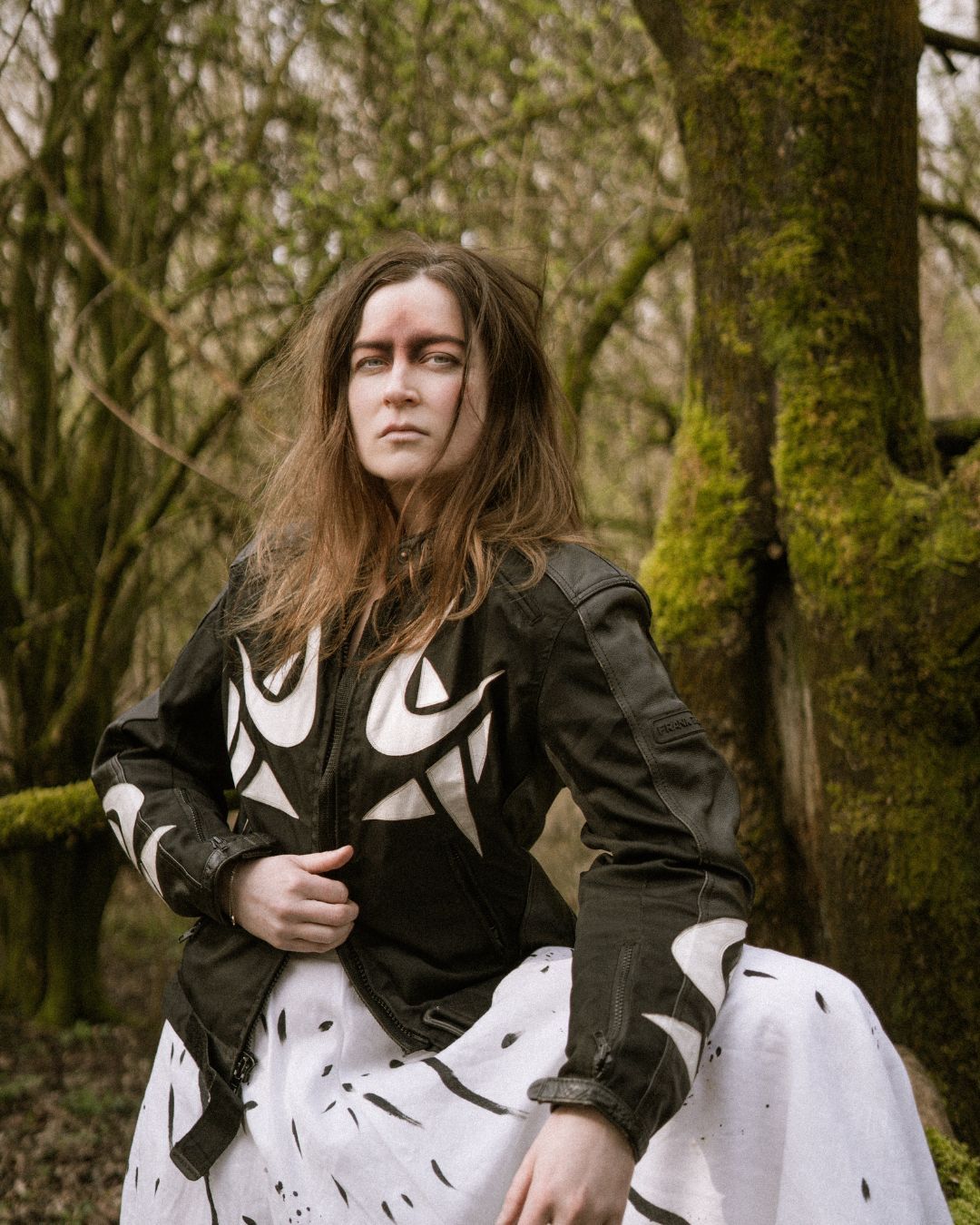 performer in black & white outfit leaning against a tree in the forest - Macbeth by HER Productions at The Dukes, Lancaster