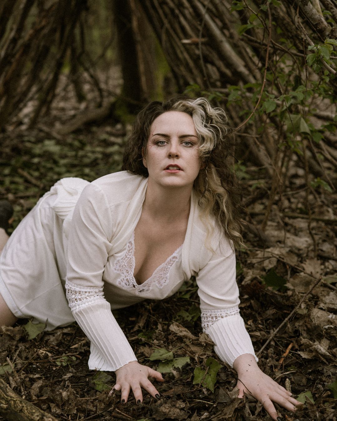 performer in white dress laying on the floor of a forest - Macbeth by HER Productions at The Dukes, Lancaster