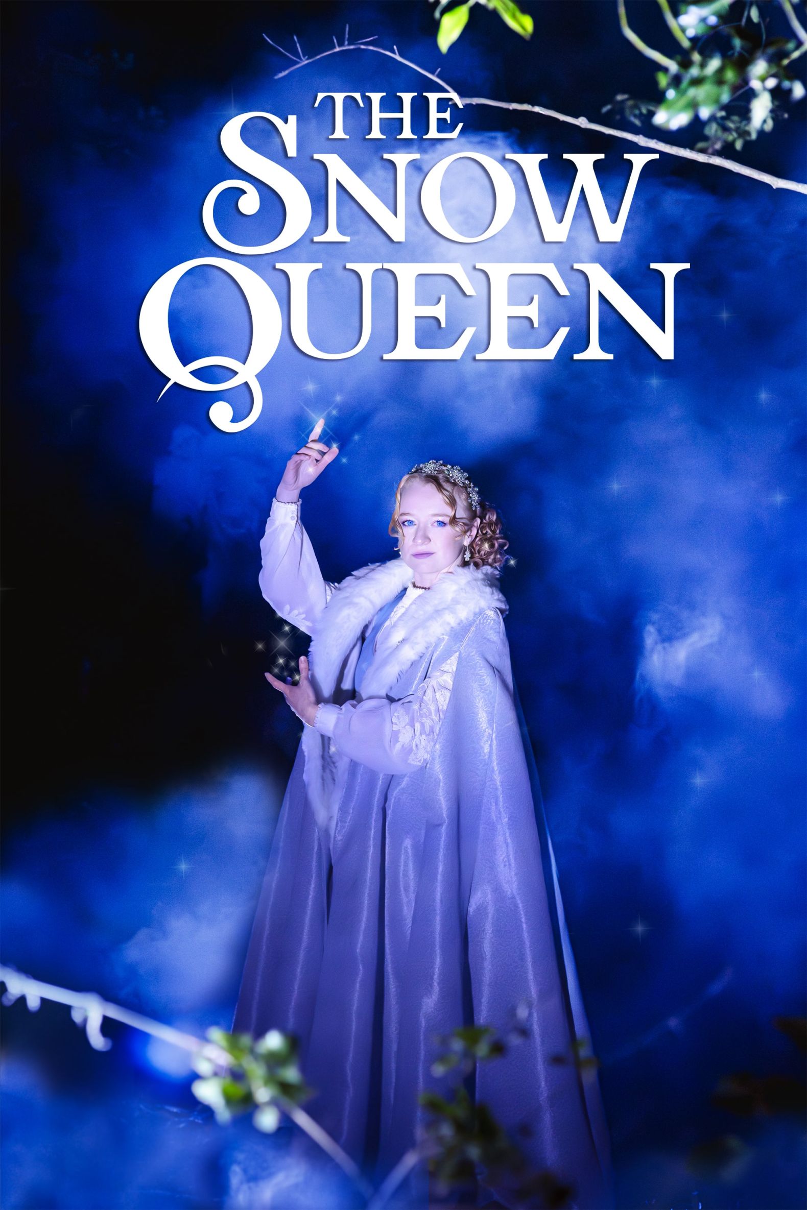 The Snow Queen at The Dukes - The Snow Queen stands in a forest and white and blue smoke swirl around her.