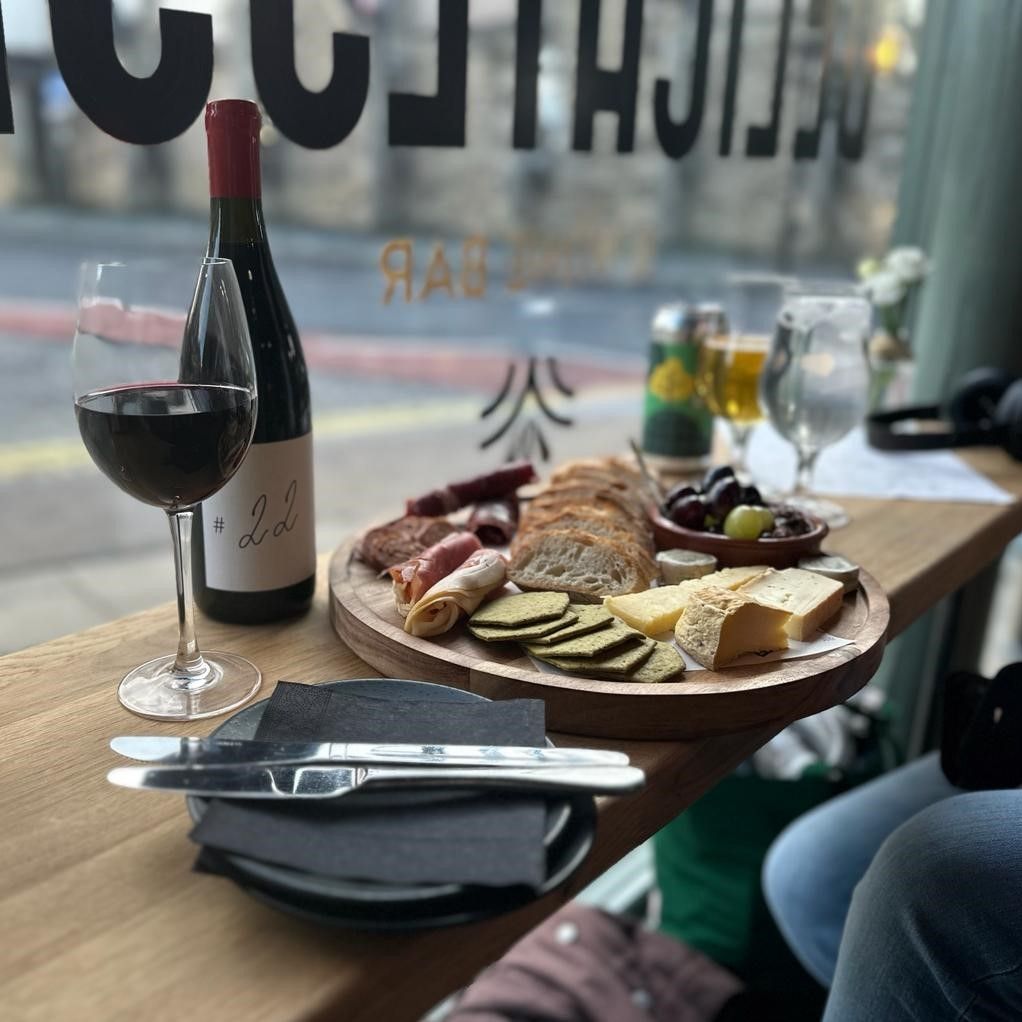 a cheese charcuterie board next to a glass of red wine