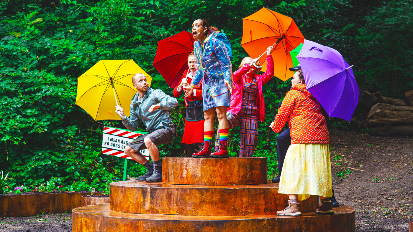 Dorothy (Hope Yolanda) stands at the top of the platform, surrounded by Miss F (Lisa Howard), her aunt (Helen Longworth) and uncle (Gareth Cassidy) holding umbrellas. The Wizard of Oz by the Dukes, photos by Gabi Dawkins.