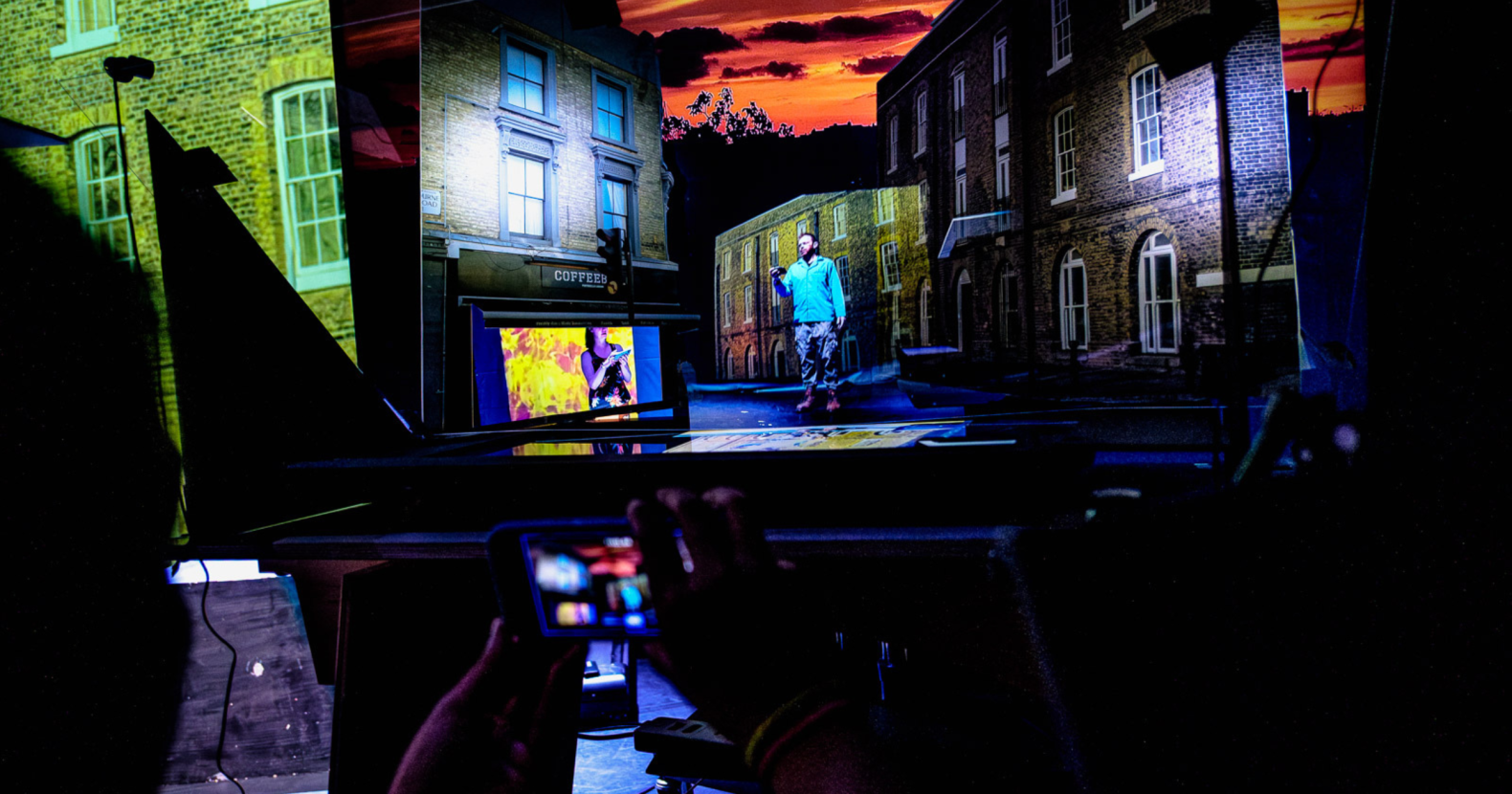 two screens that feature a projection of a street with houses, and a man and a woman who are standing in front.