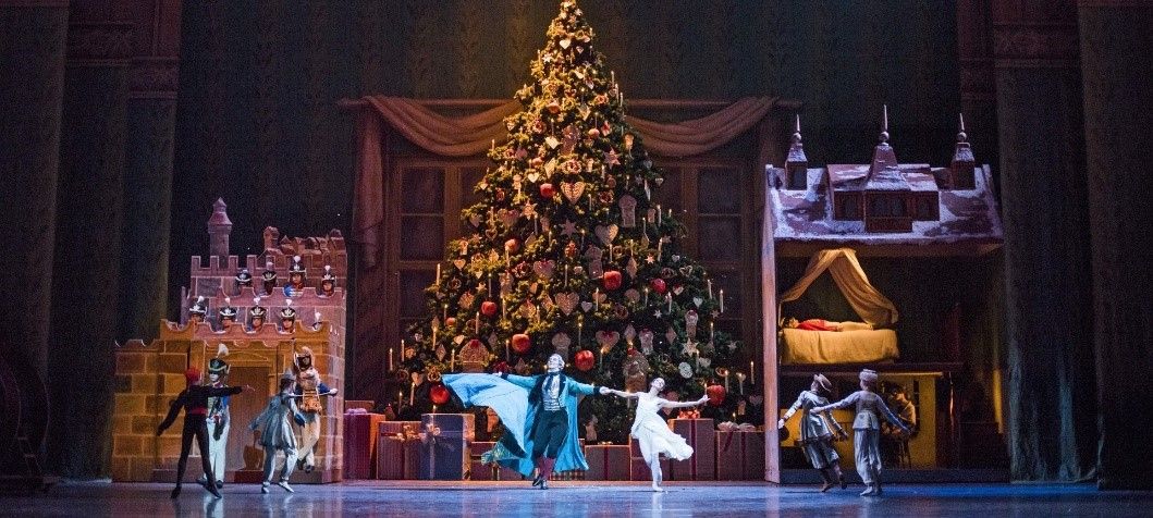 ROH The Nutcracker Production Still: Clara dancing in front of a giant, ornate Christmas tree