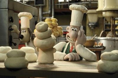 Wallace and Gromit in a bakery.  They are both wearing chef hats and there are piles of dough on the table in front of them