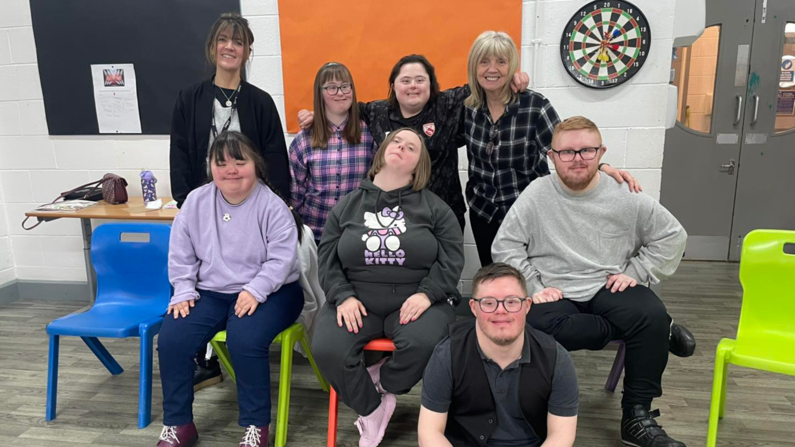 Members of Unique Kidz and their leader sitting and standing together alongside Carly Henderson. 