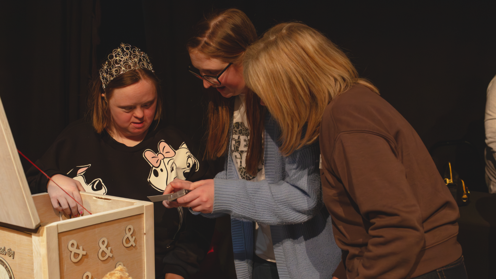 Members of Unique Kidz reading a tag they took out the wooden box in front of them.