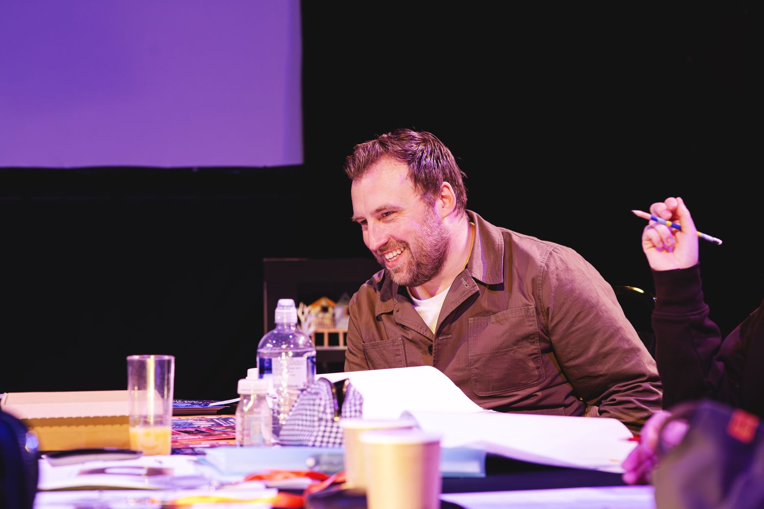 Director Chris Lawson laughing at a table during a script readthrough
