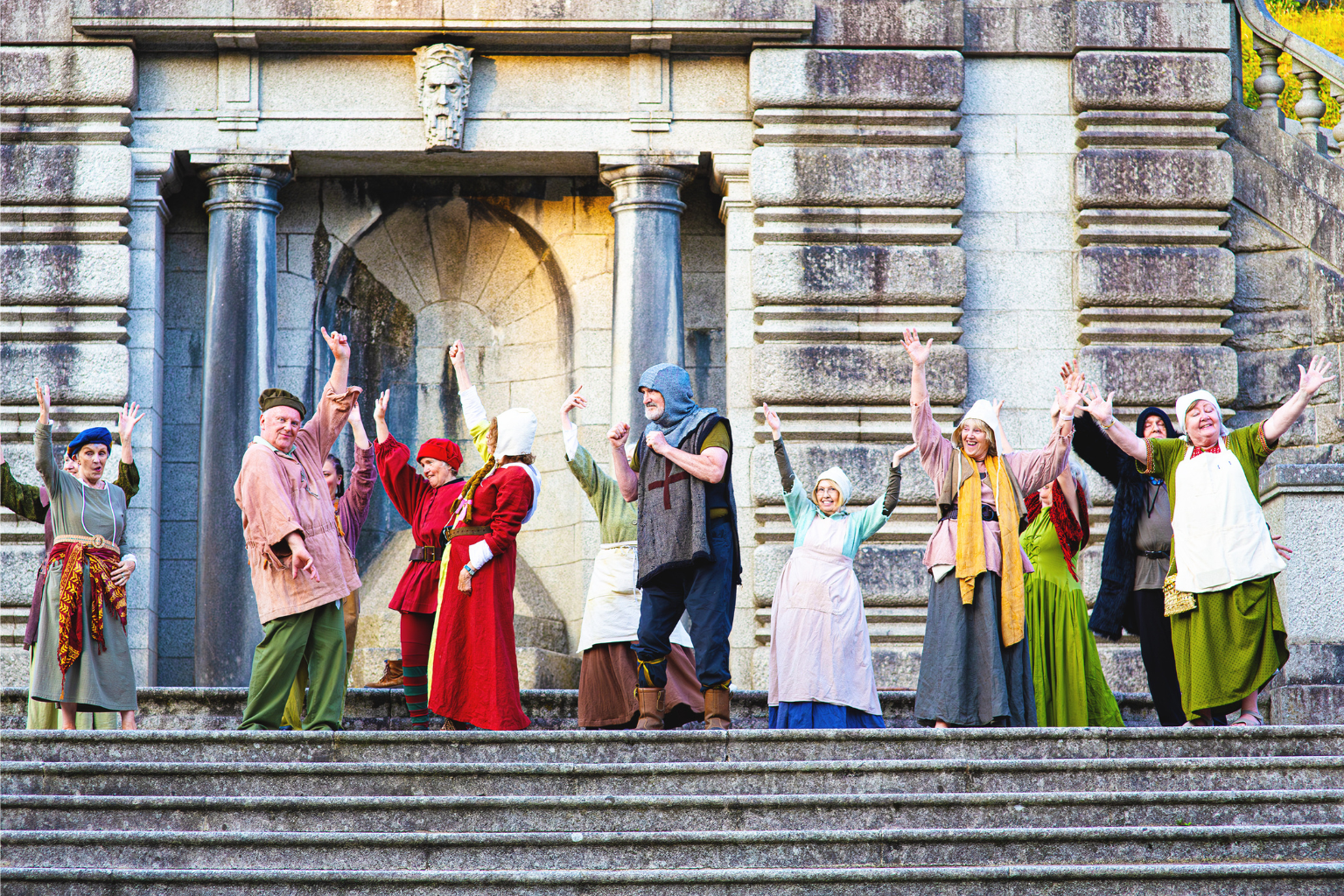The Community Chorus dancing on the monument steps in medieval costume