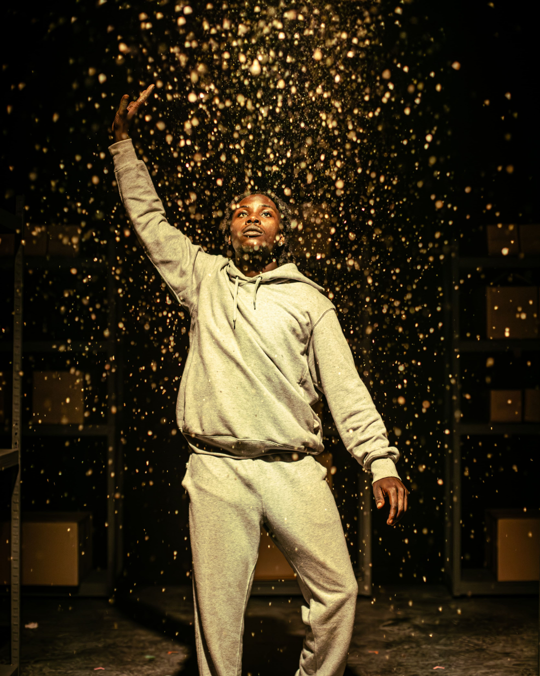 a performer with one arm raised above them, showered in what looks like gold glitter
