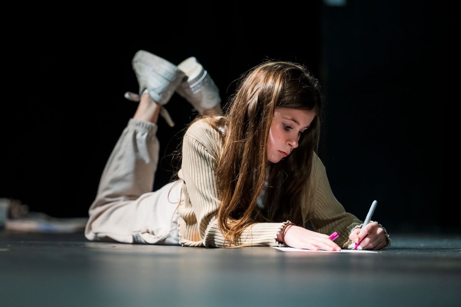 A young person lay on the ground writing