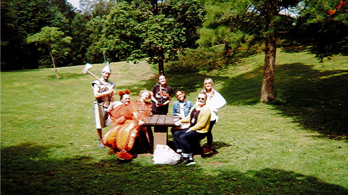 The Cast, Laura O'Connor, Elvi Piper and Gabi Dawkins sitting at a table in the park. Photo taken by The Wizard of Oz Team. 