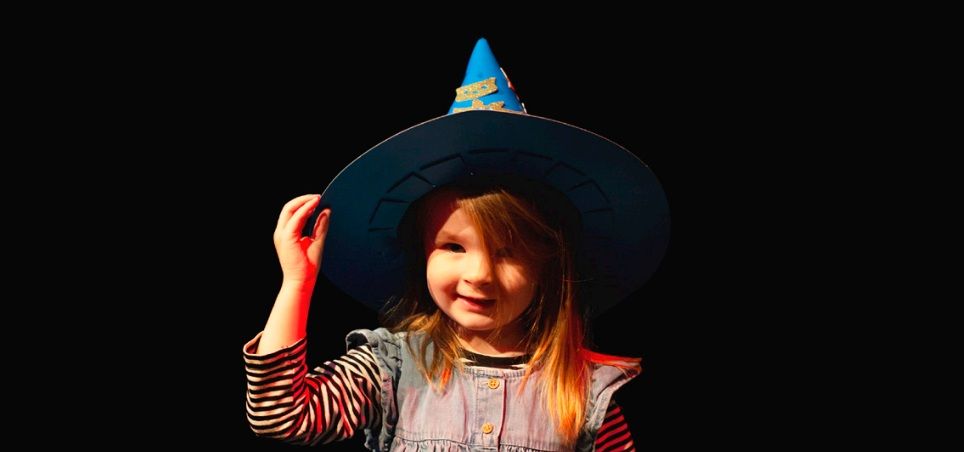 a young child wearing a craft witches hat