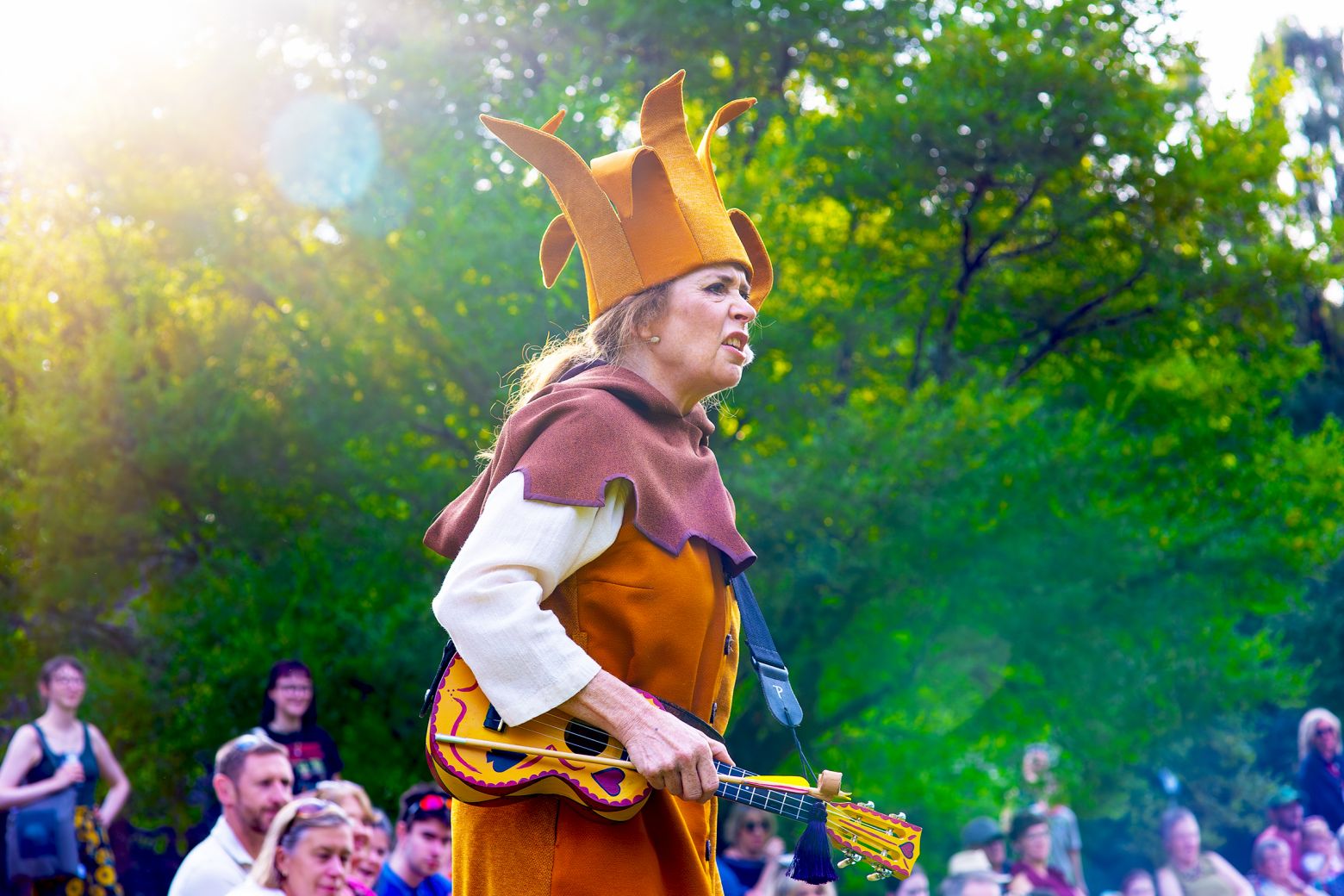 Lisa Howard a Tuck looks on bemused, holding a ukulele and arrow.