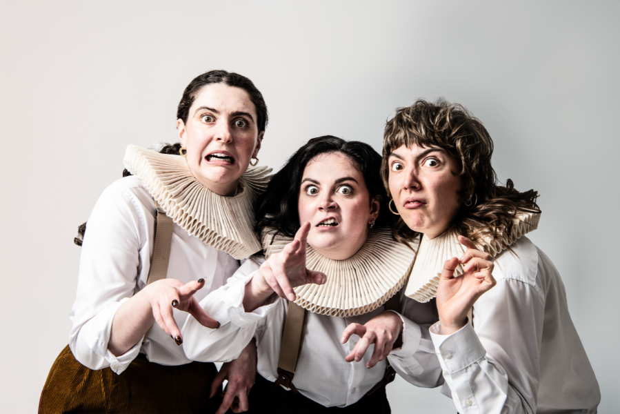 A promotional image of the Handlebards team in Macbeth. Three members look at the camera doing witchy poses.