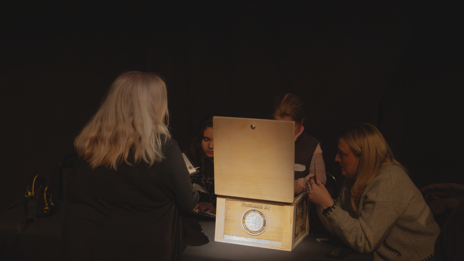 Members of the Traveller Heritage group and Sophie Hodgson sitting around a table with a wooden box. 