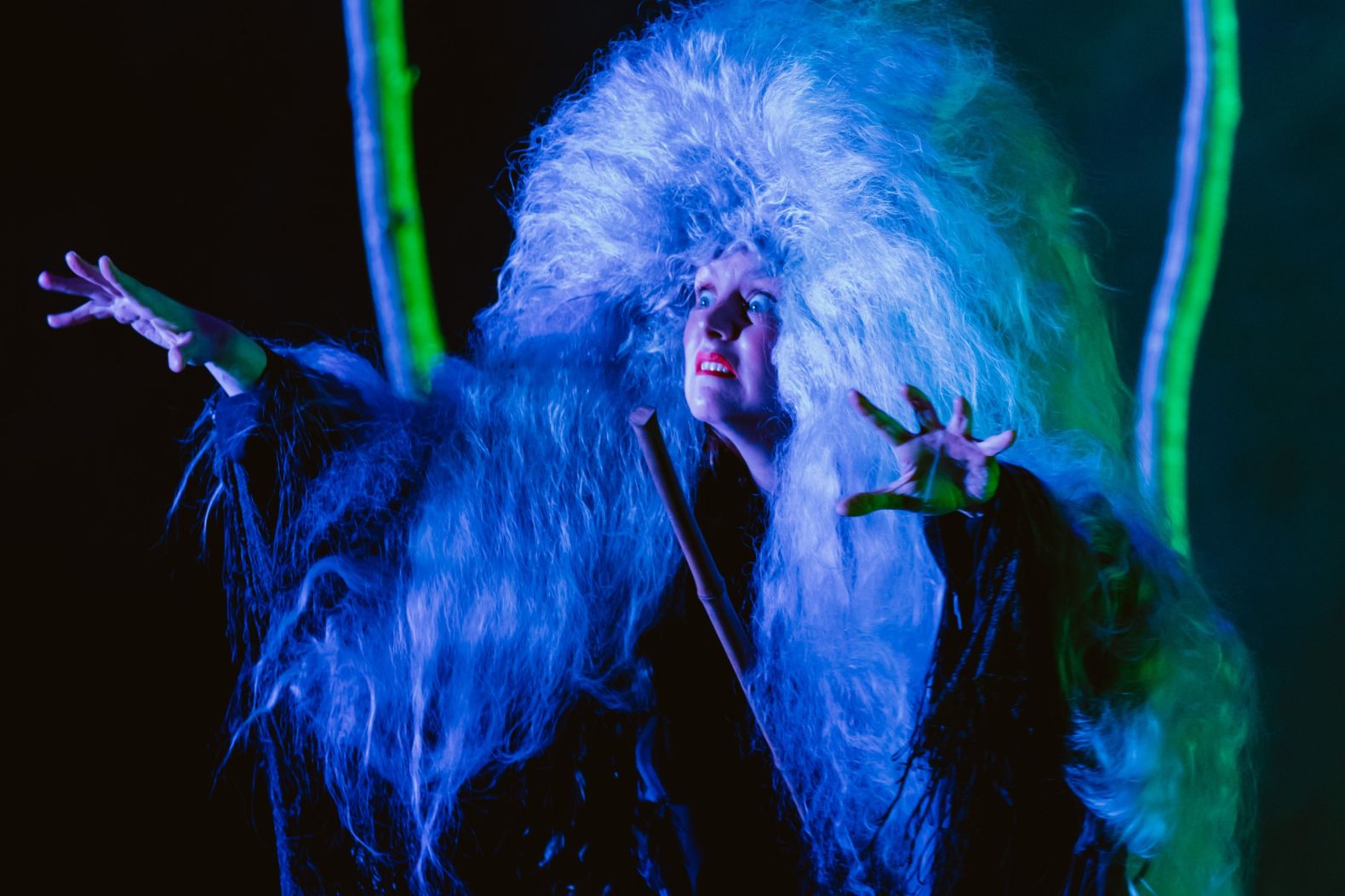 Bryony Kimmings performing in Bog Witch. Bryony is wearing a huge white wig and scowling dramatically like a witch.
