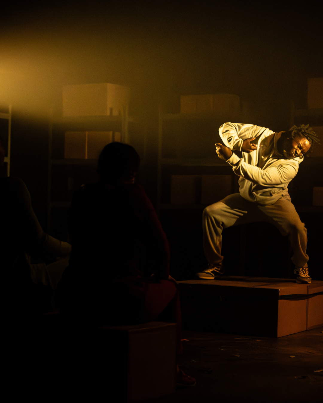 A performer is in the corner of the photo. On a dark shadowy stage, he seems lost in dance