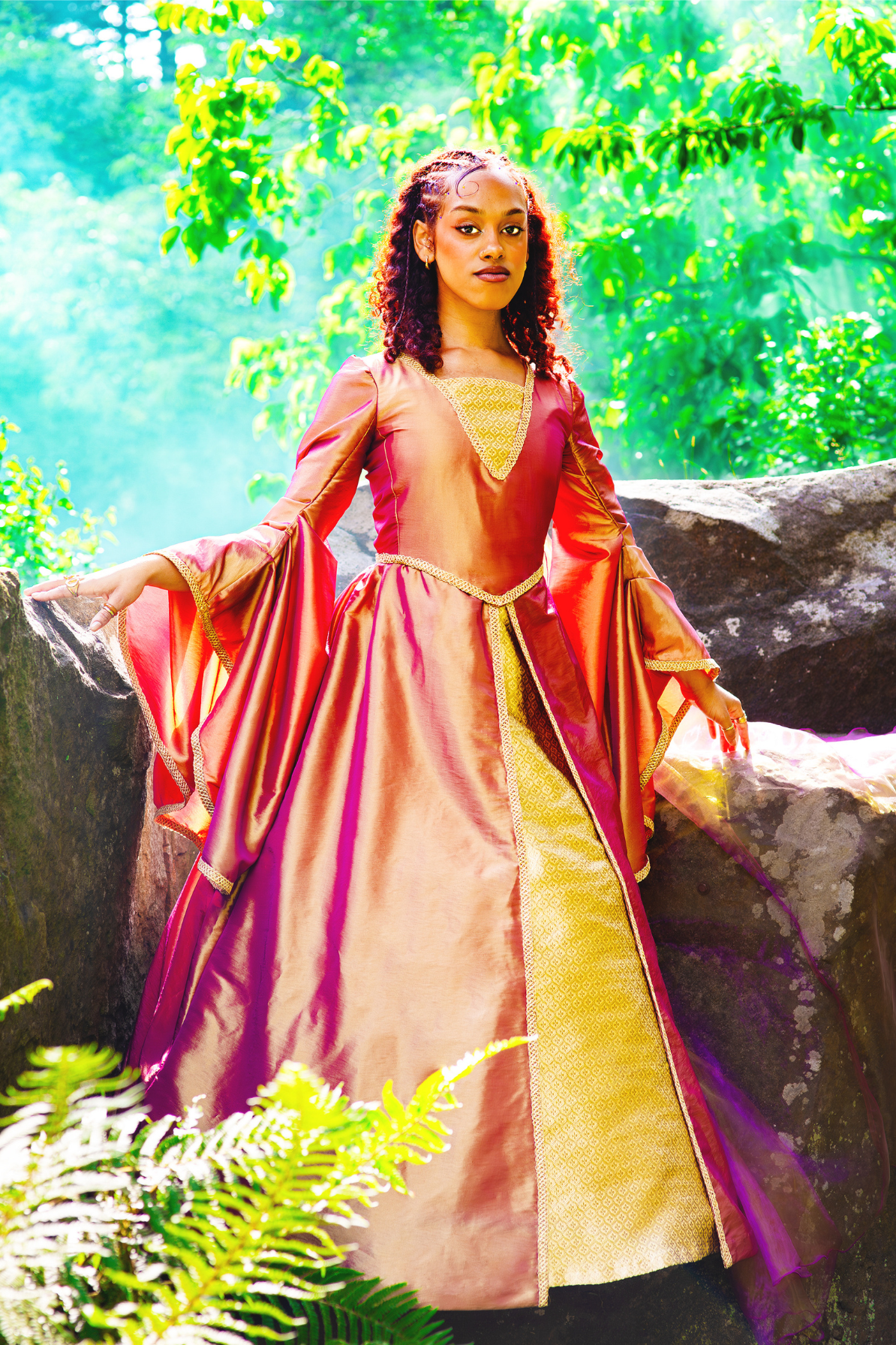 Maid Marian in front of some rocks in the park, wearing a peach and gold coloured dress