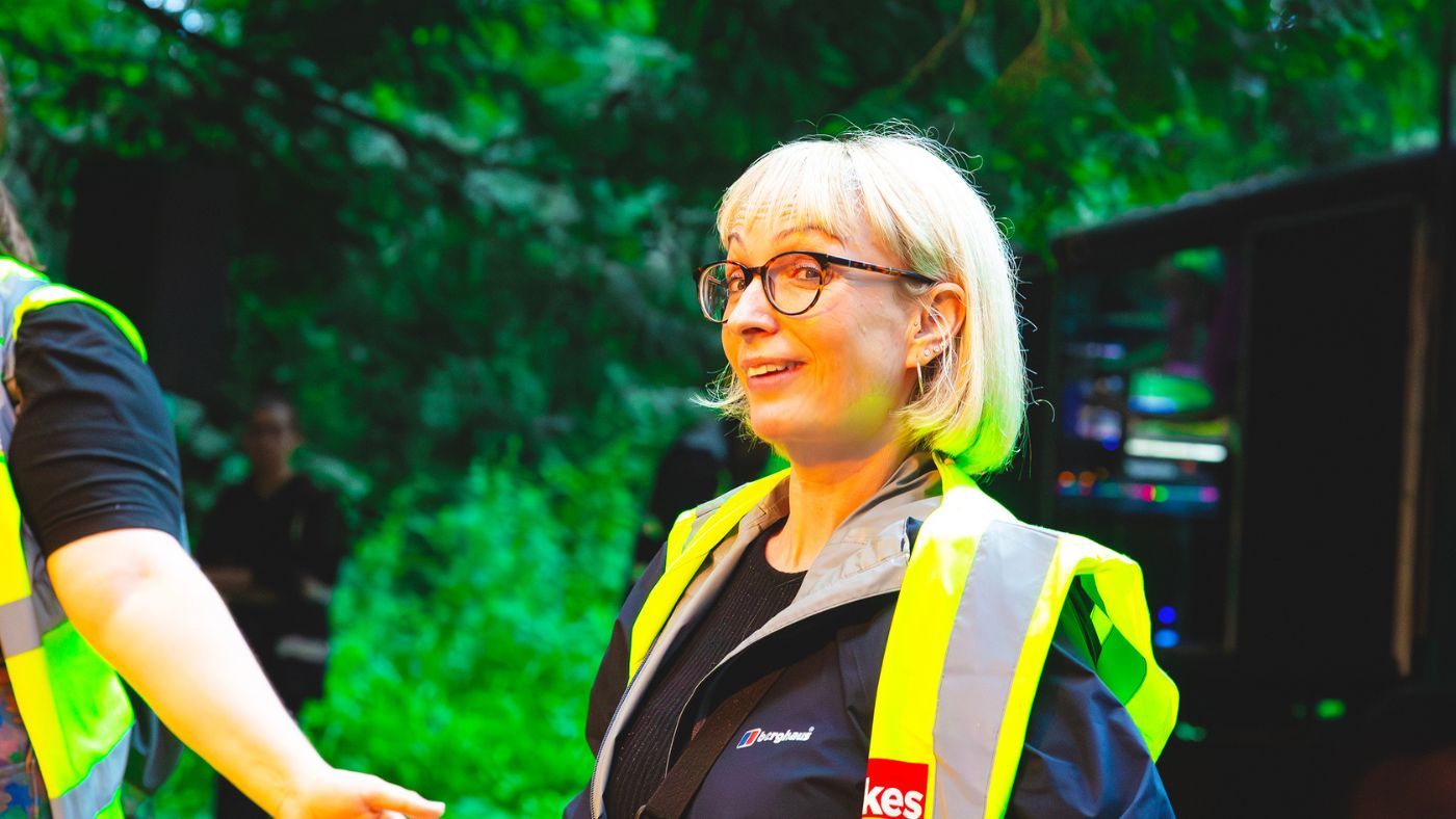 Rachel Wilkinson, a Visitor Experience Assitant, wearing all black with a yellow hi-vis jacket on top and wearing black leopard print glasses. The Wizard of Oz by the Dukes, photos by Gabi Dawkins.